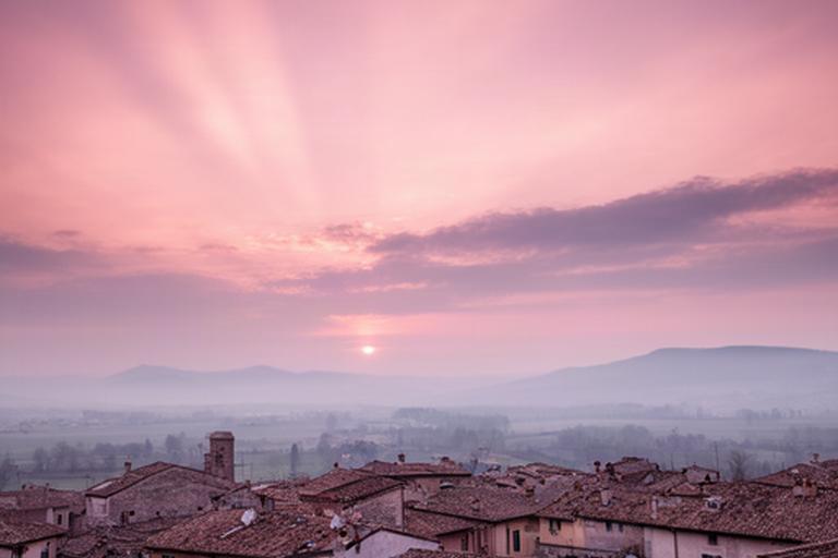 Alba rosa sopra i tetti di Spilimbergo con nuvole alte e luce radente