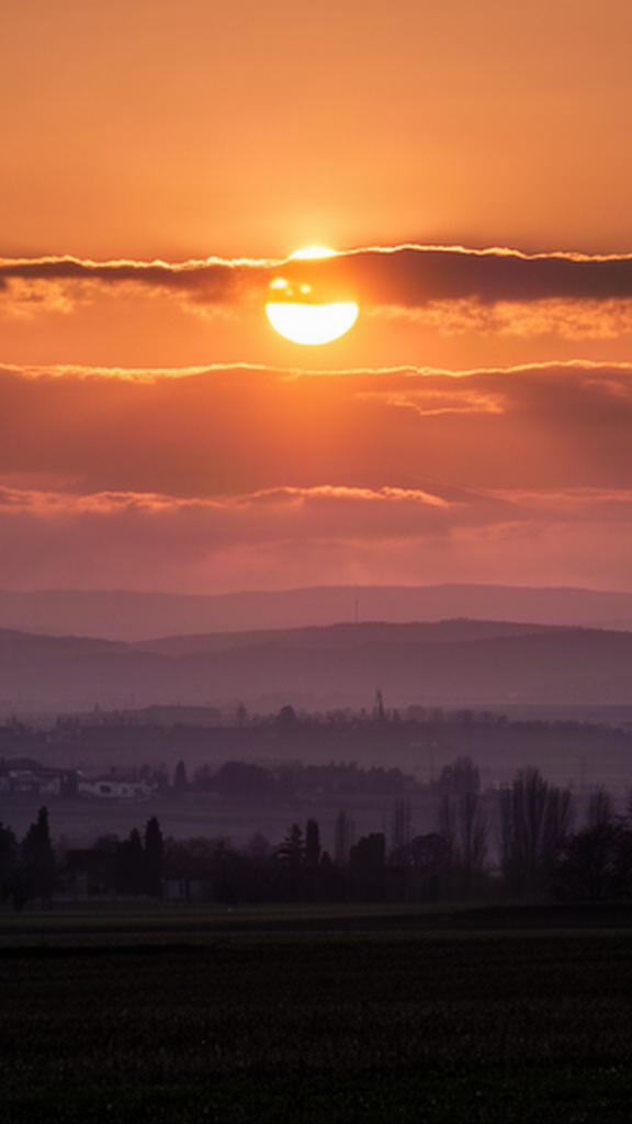 Tramonto arancio sul Friuli Venezia Giulia con strati nuvolosi bassi